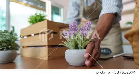 Sustainability in Action: A gardener arranging a potted plant on a table 137618974