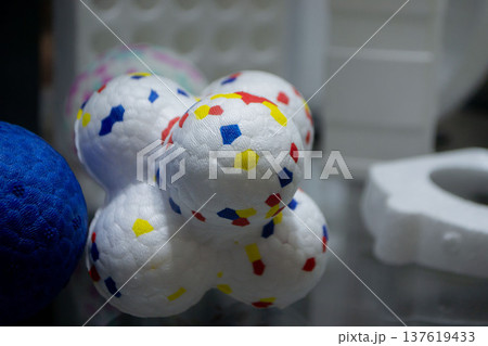 White dog toy. Durable foam dog ball close-up. Shape of connected balls, multi-colored pattern. Object made of material expanded polypropylene EPP, universal foam. New modern industrial technologies. White dog toy. Durable foam dog ball close-up. Shape of connected balls, multi-colored pattern. Object made of material expanded polypropylene EPP, universal foam. New modern industrial technologies. 137619433