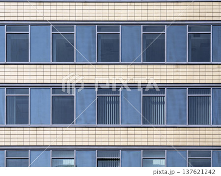 Modern Office Building Facade With Repetitive Blue Windows and Beige Tile Panels Pattern Modern Office Building Facade With Repetitive Blue Windows and Beige Tile Panels Pattern 137621242