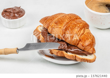 Chocolate croissant with coffee and knife spreading chocolate Chocolate croissant with coffee and knife spreading chocolate 137621440