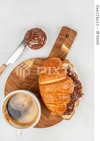 Chocolate croissant with coffee and spread on wooden board Chocolate croissant with coffee and spread on wooden board 137621442