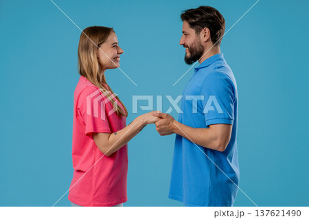 Love confession. Happy couple stands on blue, holding hands, look into eyes. Romantic feelings, perfect relationships. Love confession. Happy couple stands on blue, holding hands, look into eyes. Romantic feelings, perfect relationships. 137621490