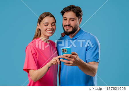 Young Couple Using Mobile Device. Woman Man Watching, Laughing With Smartphone Young Couple Using Mobile Device. Woman Man Watching, Laughing With Smartphone 137621496