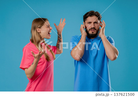 Grumpy Woman Quarrels On Husband Or Boyfriend On Blue. Tired Man Shut His Ears Grumpy Woman Quarrels On Husband Or Boyfriend On Blue. Tired Man Shut His Ears 137621500