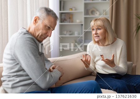 Senior couple experiencing relationship conflict while talking on sofa at home Senior couple experiencing relationship conflict while talking on sofa at home 137621630