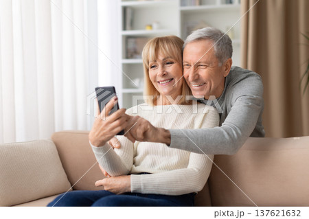 Happy senior couple sitting on sofa at home taking selfie with smartphone 137621632