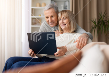 Senior couple sitting on sofa using laptop together at home 137621643