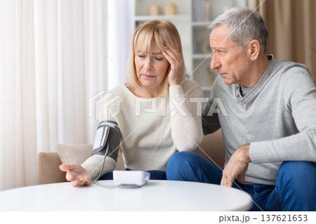 Senior woman measuring blood pressure at home while feeling unwell Senior woman measuring blood pressure at home while feeling unwell 137621653