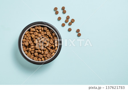 A bowl of dry dog food on a isolated blue background. 137621783
