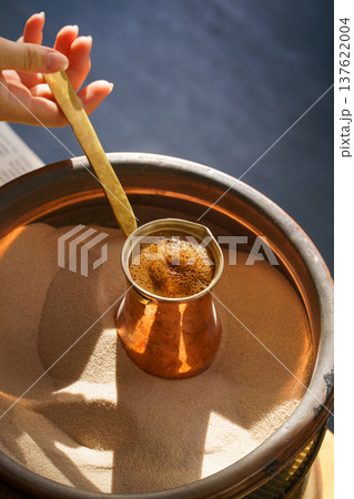 making Turkish coffee in a cezve on the sand, fresh coffee drink making Turkish coffee in a cezve on the sand, fresh coffee drink 137622004