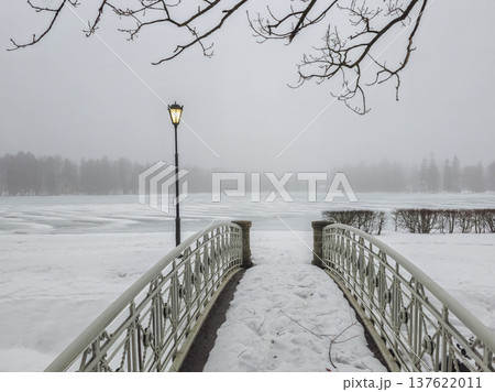 Snow blankets a quiet wooden bridge over frozen water Snow blankets a quiet wooden bridge over frozen water 137622011