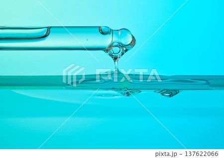 Pipette dripping liquid drop into blue water surface Pipette dripping liquid drop into blue water surface 137622066