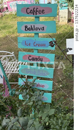 Colorful signpost in garden with directions to coffee, baklava, ice cream, and other treats Colorful signpost in garden with directions to coffee, baklava, ice cream, and other treats 137622234