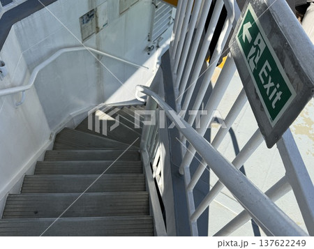 Exit sign and metal staircase on a ship deck under bright sunlight, with a nautical theme Exit sign and metal staircase on a ship deck under bright sunlight, with a nautical theme 137622249