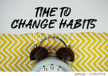 Time to Change Habits text written on paper rip with alarm clock flat lay on yellow chevron background 137623759