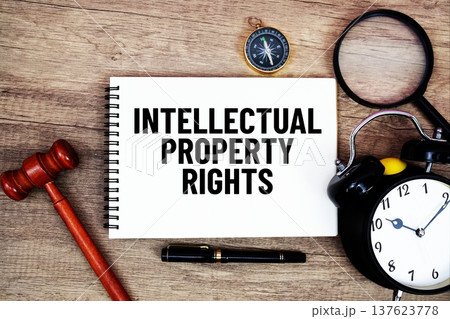 Intellectual Property Rights message written on notepad with alarm clock, wood gavel and magnifying glass flat lay on wooden background 137623778