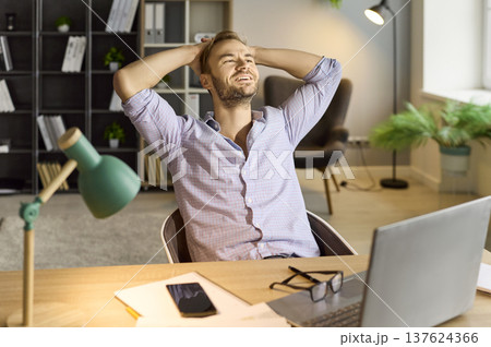 Relaxed businessman smiling after achievement at desk with laptop in office Relaxed businessman smiling after achievement at desk with laptop in office 137624366