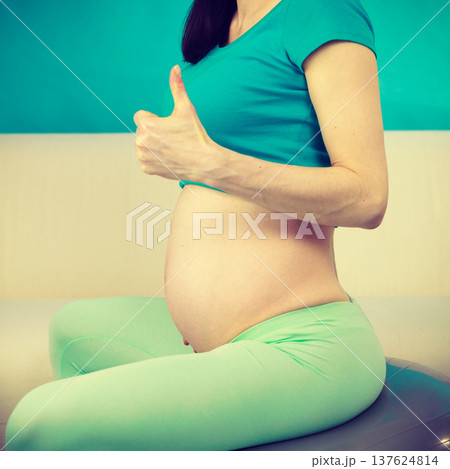 Pregnant woman sitting on fit ball, thumb up gesture Pregnant woman sitting on fit ball, thumb up gesture 137624814