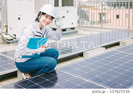 ソーラーパネルの点検をする女性作業員 ソーラーパネルの点検をする女性作業員 137625530