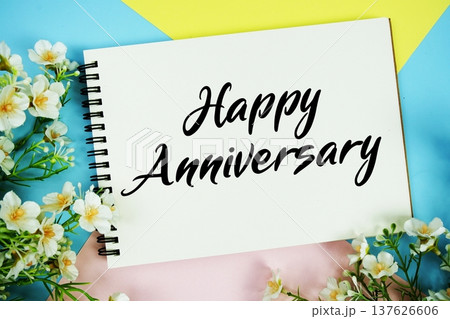 Happy Anniversary text written on notepad with flowers decorations flat lay on multicolor pastel background 137626606