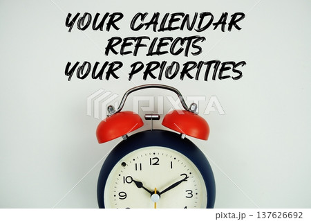 Your Calendar Reflects Your Priorities text with alarm clock flat lay on white background Your Calendar Reflects Your Priorities text with alarm clock flat lay on white background 137626692