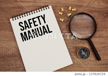 Safety Manual text written on notepad with compass and magnifying glass flat lay on wooden background 137626729