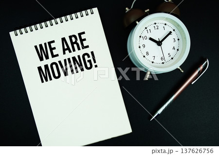 We Are Moving text written on notepad with pen and alarm clock We Are Moving text written on notepad with pen and alarm clock 137626756