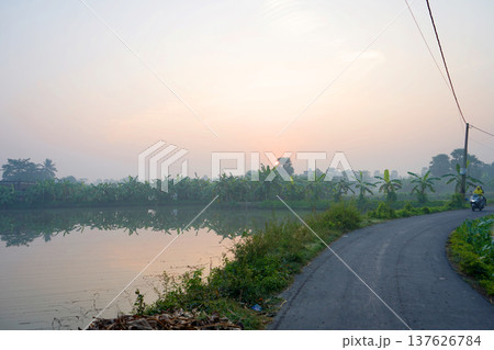 Winding Village Road along a Scenic Lake at Sunrise 137626784
