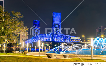 Beautiful night view of the illuminated Main Street Bridge and Friendship Fountain in downtown Jacksonville, Florida, with city lights and urban architecture. Beautiful night view of the illuminated Main Street Bridge and Friendship Fountain in downtown Jacksonville, Florida, with city lights and urban architecture. 137627156