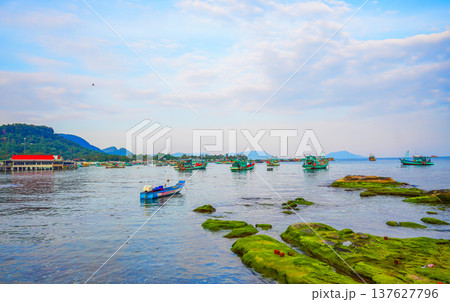 Fishing boats at shore as clouds cover sky. Fishermen boats in sea at rocky shore in fishing village 137627796