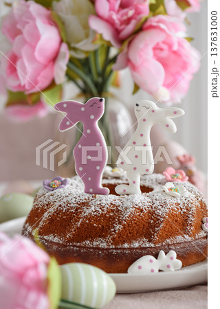 Traditional easter cakes with icing decorated with gingerbread cookies in shape of rabbits on white wooden table 137631000