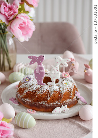 Traditional easter cakes with icing decorated with gingerbread cookies in shape of rabbits on white wooden table 137631001
