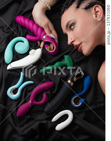Portrait of Caucasian woman lying on bed among sex toys. Portrait of Caucasian woman lying on bed among sex toys. 137631060