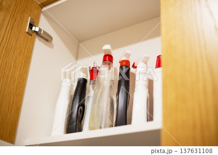 Cleaning spray bottles storing in kitchen cupboard 137631108