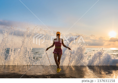 Fit woman jumping rope at the beach during summer vacation Fit woman jumping rope at the beach during summer vacation 137631158
