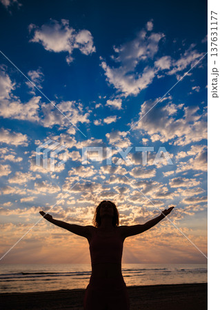 Happy woman enjoying sunrise at the beach during summer vacation Happy woman enjoying sunrise at the beach during summer vacation 137631177