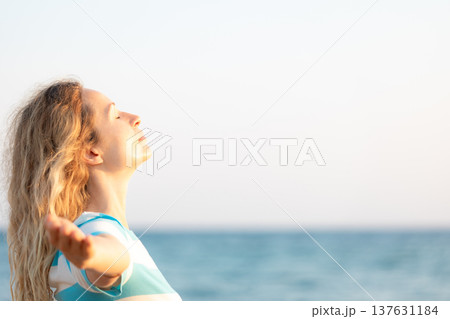 Young happy woman enjoying by sunrise against blue sea and sky on summer vacation Young happy woman enjoying by sunrise against blue sea and sky on summer vacation 137631184
