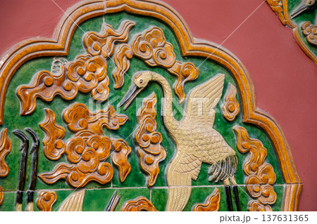 Ornate glazed tile relief of crane on traditional temple wall Ornate glazed tile relief of crane on traditional temple wall 137631365