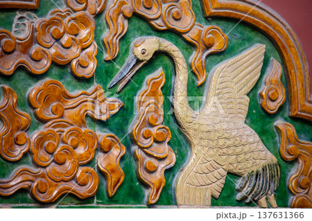 Ornate glazed tile relief of crane on traditional temple wall 137631366