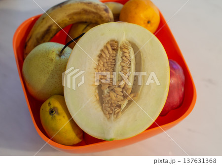 Assorted fruit in orange bowl with halved melon Assorted fruit in orange bowl with halved melon 137631368