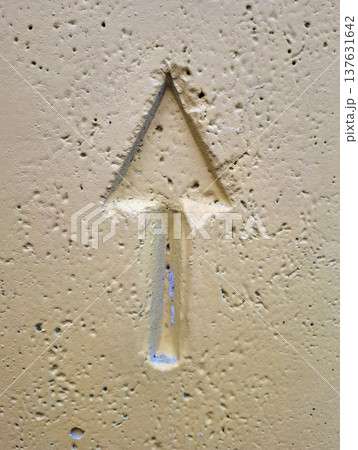 An upward-pointing arrow pressed into yellow-painted concrete 137631642