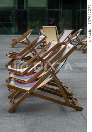 The Wooden deck chairs are arranged in a diagonal recession, creating strong leading lines that draw the eye from the foreground toward the background. The Wooden deck chairs are arranged in a diagonal recession, creating strong leading lines that draw the eye from the foreground toward the background. 137632279