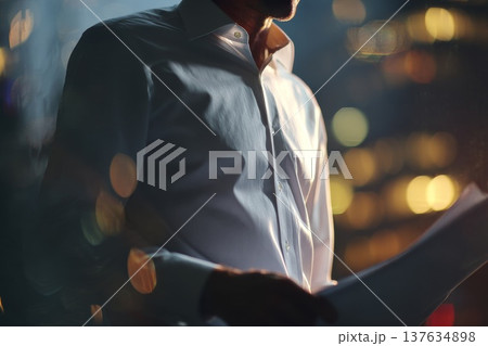 Man in a white shirt holding a piece of paper, deep in thought, contemplating important information in an urban setting. Man in a white shirt holding a piece of paper, deep in thought, contemplating important information in an urban setting. 137634898