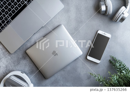 Modern workspace featuring a laptop, headphones, and a smartphone arranged neatly on a wooden table. Modern workspace featuring a laptop, headphones, and a smartphone arranged neatly on a wooden table. 137635266