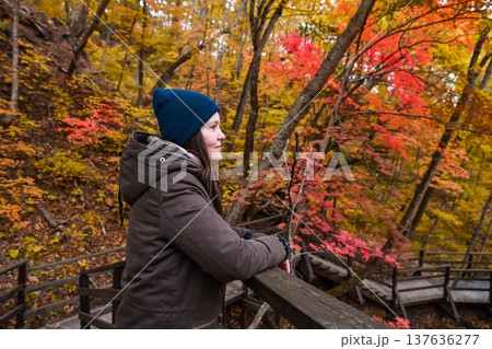 Russian woman 35 years old solo traveler standing on forest stairs looking into distance in autumn nature reflecting thinking and mindful solo journey Russian woman 35 years old solo traveler standing on forest stairs looking into distance in autumn nature reflecting thinking and mindful solo journey 137636277