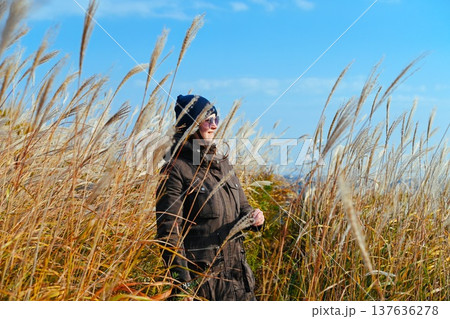 Russian woman 35 years old touching miscanthus grass in autumn field Far East Russia focusing on sensory experience mindfulness and connection with nature 137636278