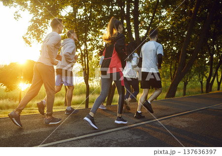 Full-length view, group of people running outdoors on paved path 137636397