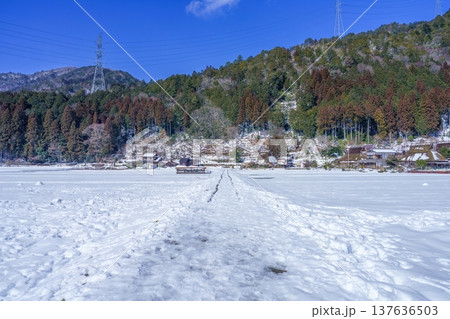 美山かやぶきの里で見た雪に覆われた日本の伝統的な茅葺き屋根の集落と冬の青空 137636503