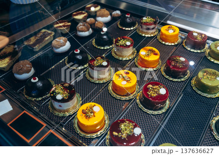 Cakes and pastries are displayed in a glass case at a bakery in the afternoon 137636627