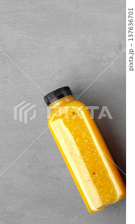 Orange juice bottle on a gray surface in a bright setting in the afternoon sun 137636701